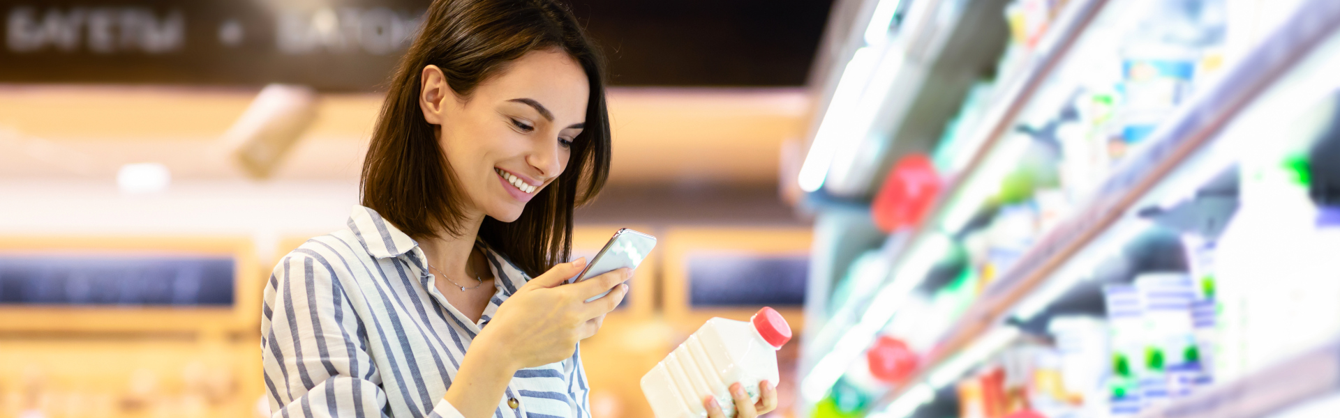 Frau im Supermarkt scannt mit dem Smartphone eine Getränkeflasche.